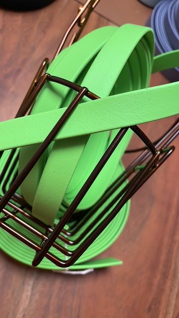 Bunte, grüne Bänder in einem Metallständer auf einem Holzuntergrund.