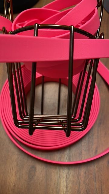 Rosa Gummiband, aufgerollt und teilweise in einem schwarzen Drahtkorb.