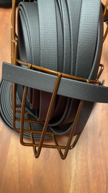 Schwarze Riemen in einem braunen Metallgestell auf einer Holzoberfläche.